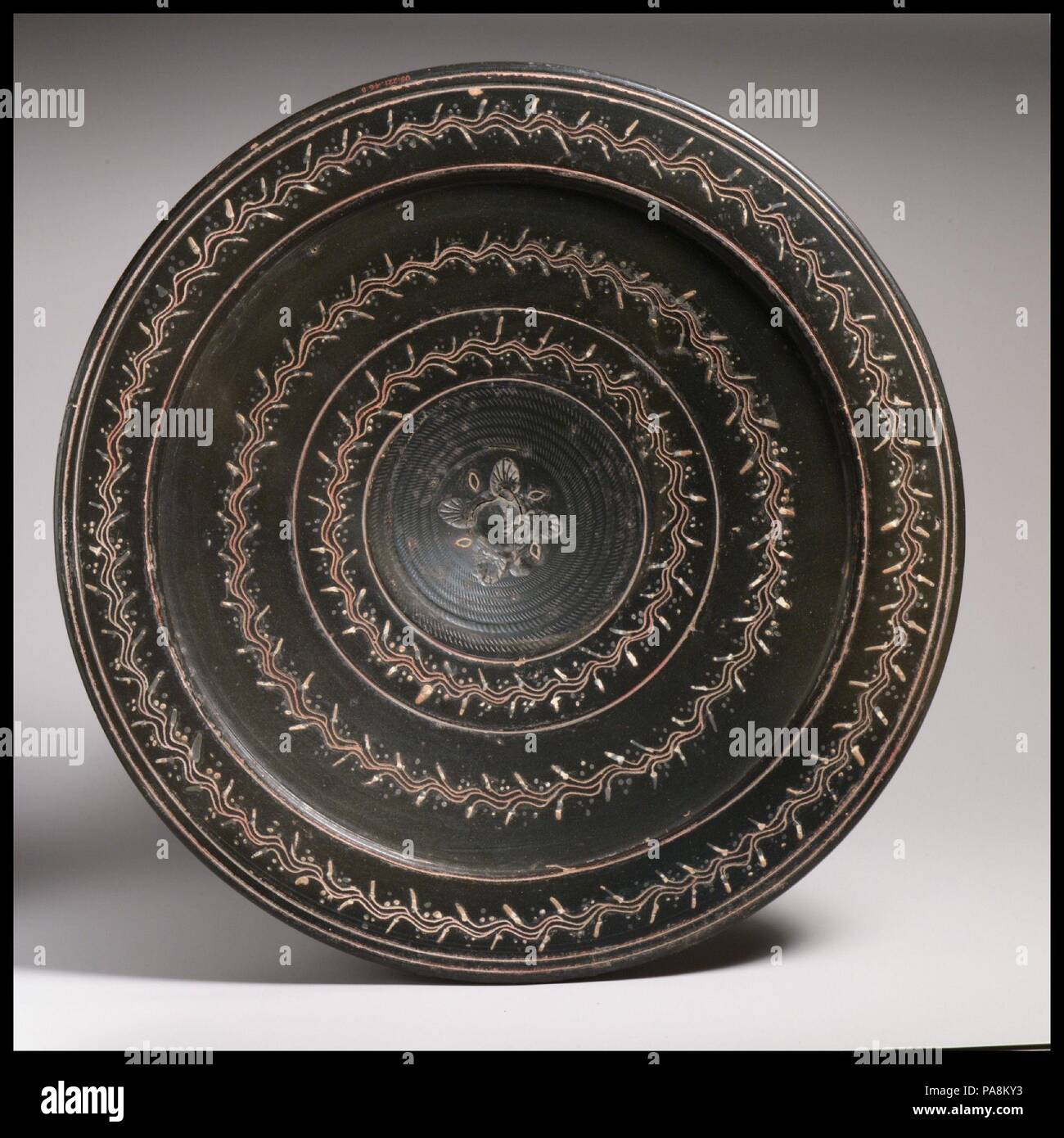 Terracotta plate. Culture: Greek, South Italian, Campanian, Teano. Dimensions: diameter  13in. (33cm). Date: ca. 330-300 B.C..  Plate of black glaze on which decorations are painted in various colors. Museum: Metropolitan Museum of Art, New York, USA. Stock Photo