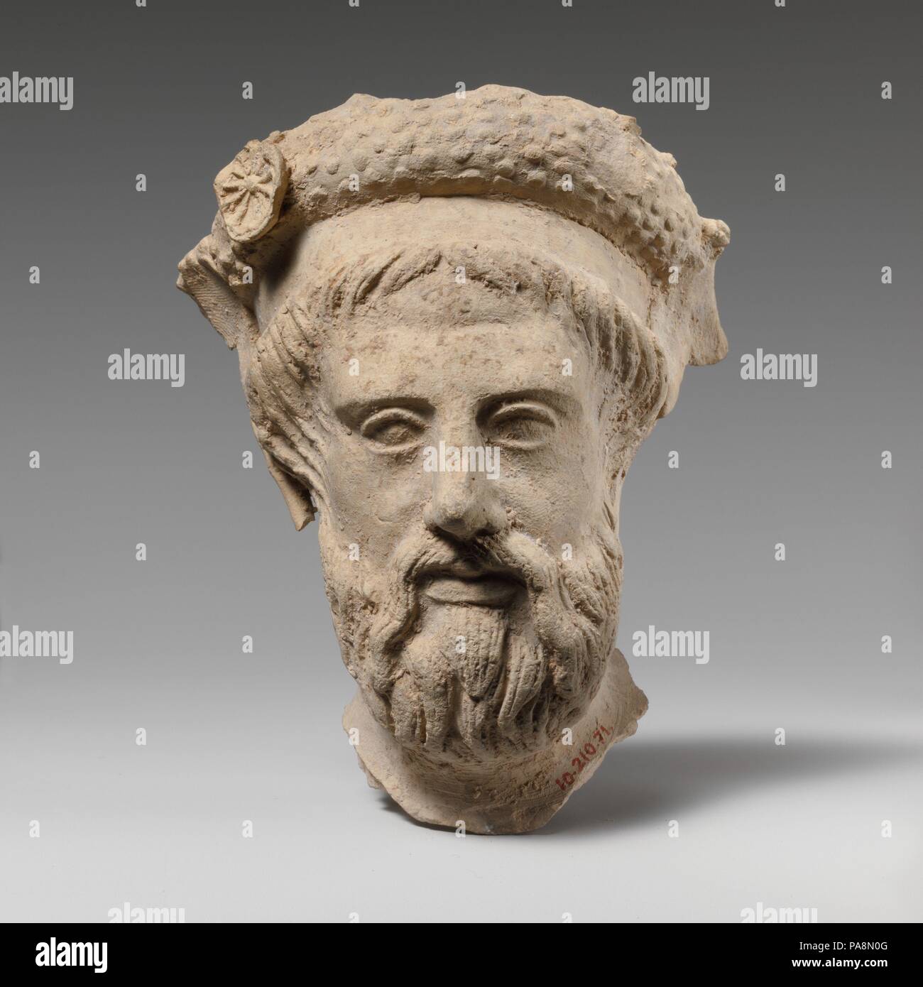 Terracotta head of a bearded man. Culture: Greek, South Italian, Tarentine. Dimensions: H. 4 3/4 in. (12.1 cm). Date: early 4th century B.C..  The head is certainly part of a representation of a reclining figure, whose identity is unclear. He wears a flat band around his forehead and, above it, a thicker one, embellished with rosettes. Museum: Metropolitan Museum of Art, New York, USA. Stock Photo