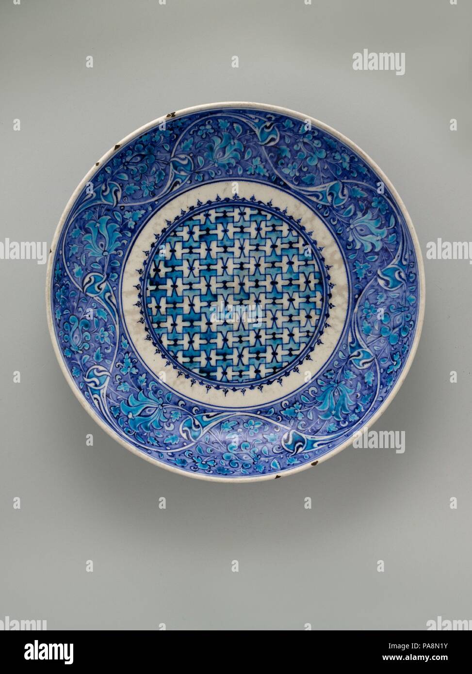 Dish. Dimensions: H. 3 in. (7.62 cm)  Diam. 15 1/2 in. (39.4 cm). Date: mid-16th century.  One of the most spectacular Iznik pieces in the Museum's collection, this saucer-shaped dish displays a palette of rich blue and bright turquoise characteristic of early Iznik ceramics. The floral scrolls on the cavetto are inspired by fifteenth-century Chinese celadon ware. Museum: Metropolitan Museum of Art, New York, USA. Stock Photo