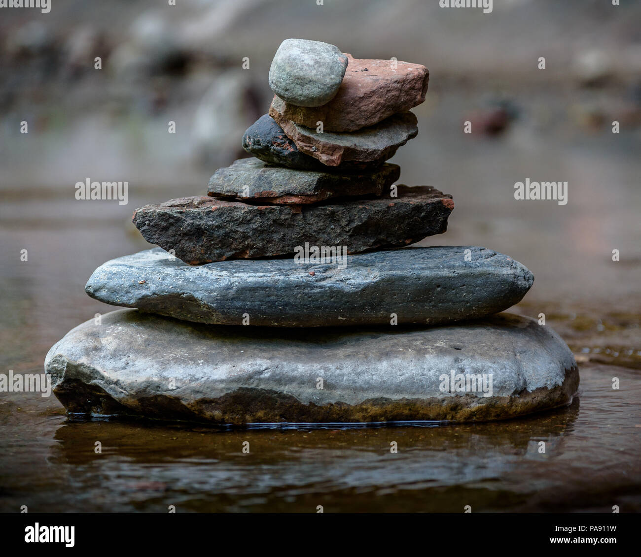 Balance and wellness concept. Close-up of river stones balanced in the shallow mountain creek. Low depth of field. Zen and spa inspired Stock Photo