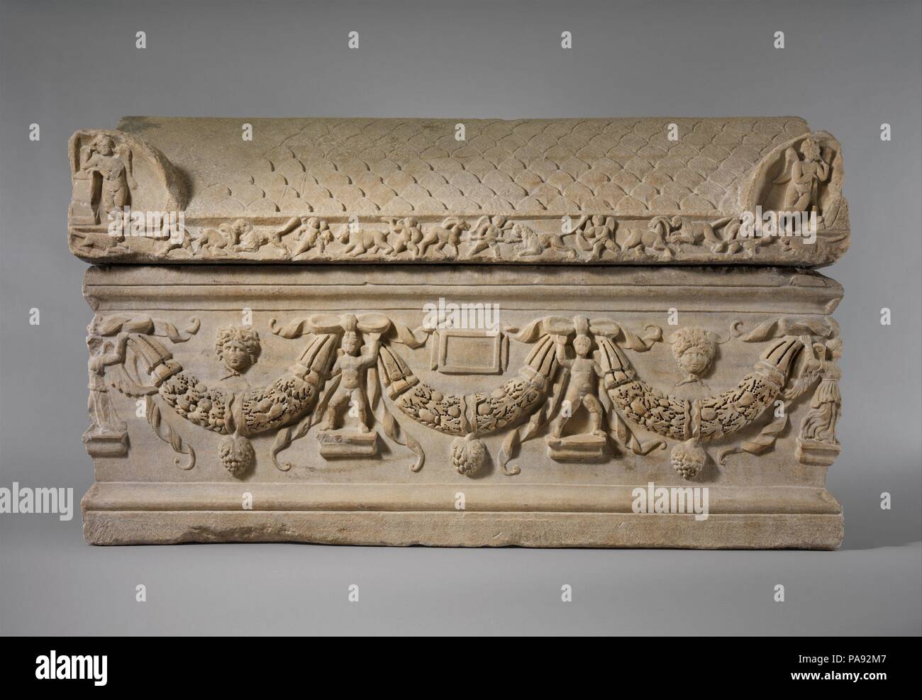 Marble sarcophagus with garlands. Culture: Roman. Dimensions: Overall: 53 x 88in. (134.6 x 223.5cm). Date: ca. A.D. 200-225.  This was the first gift accepted by the Museum.  The back and cover of this sarcophagus are unfinished, and its inscription tablet is blank, which may imply that it went unsold in antiquity. Garlands of oak leaves supported by two erotes and four Victories adorn the front and sides. Medusa heads fill the spaces above the garlands, except in the center of the front, where there is the blank inscription tablet. Six erotes hunt various wild animals along the front face of  Stock Photo