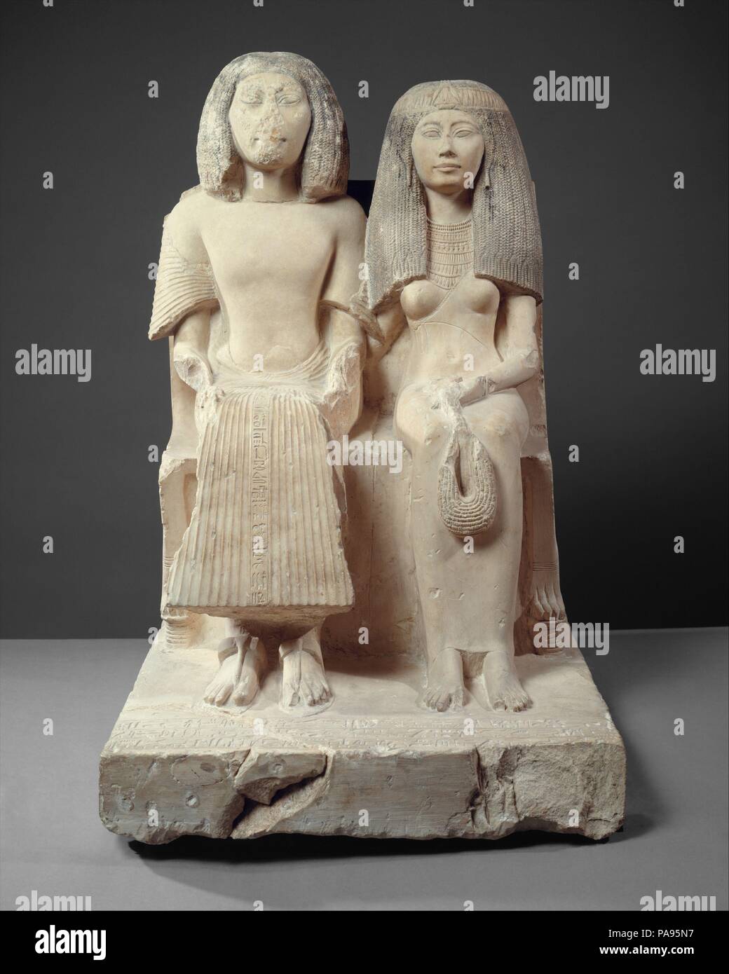 Yuny and His Wife Renenutet. Dimensions: H. 84.5 cm (33 1/4 in); w. 54.5 cm (21 7/16 in); d. 73 cm (28 3/4 in). Dynasty: Dynasty 19. Reign: reign of Seti I. Date: ca. 1294-1279 B.C..  These figures represent Yuny seated next to his wife Renenutet. Yuny, who lived in the city of Asyut, was a chief royal scribe and holder of many other offices, perhaps including that of physician. Additional inscriptions on the base of the statue further elaborate Yuny's responsibilities. On the center fold of Yuny's pleated skirt is an inscription that reads: 'May everything that comes forth upon the offering t Stock Photo