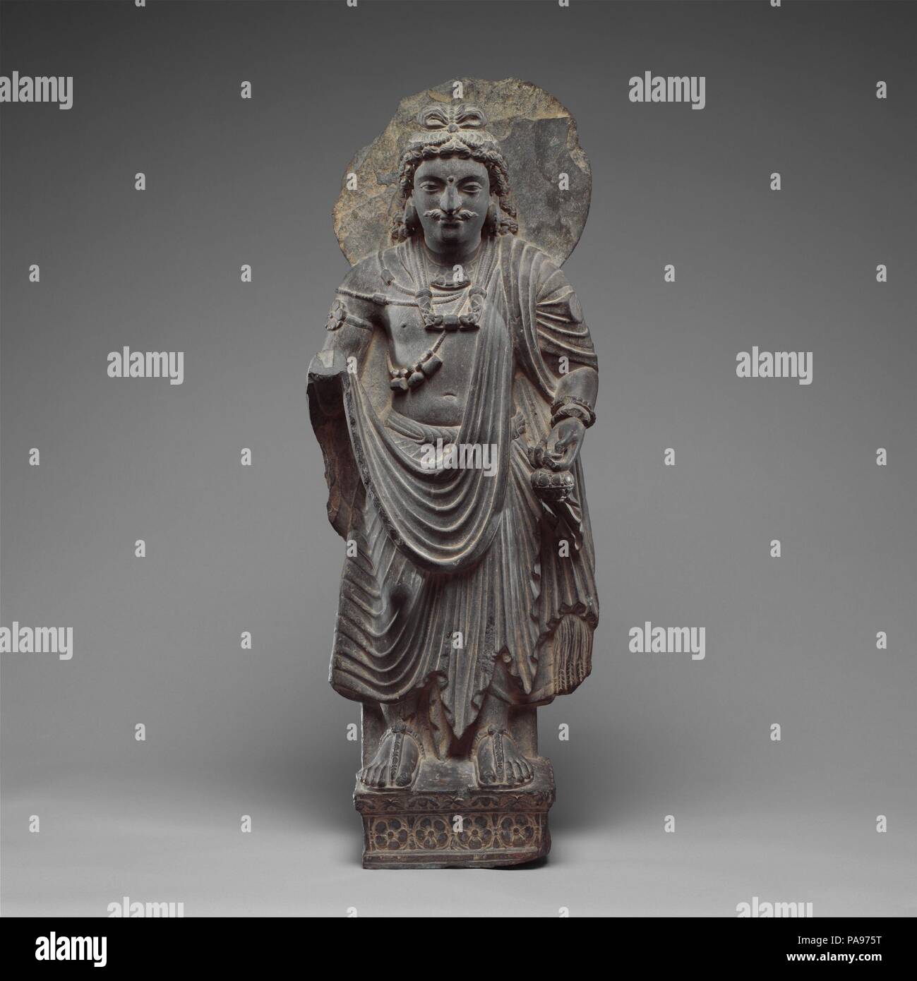 Standing Bodisattva Maitreya (Buddha of the Future). Culture: Pakistan (ancient region of Gandhara). Dimensions: H. 31 3/4 in. (80.7 cm); W. 11 1/2 in. (29.2 cm); D. 6 in. (15.2 cm). Date: ca. 3rd century.  Maitreya is the Buddha of the next age, much as Shakyamuni is the Buddha of our age. He resides in Tushita heaven waiting for his final rebirth. As befits his highest rebirth, he wears the garments and jewels of a prince, though his halo clearly demarks his deified status. He can be identified by the sacred water flask in his left hand. Museum: Metropolitan Museum of Art, New York, USA. Stock Photo