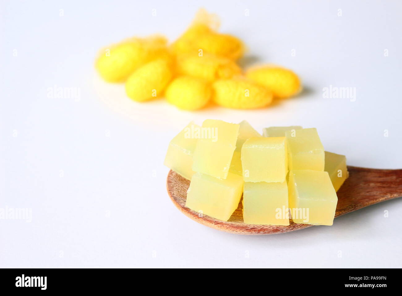 Square sliced yellow cocoon handmade glycerin soap bases on wooden paddle with blur natural yellow cocoons on background. Stock Photo