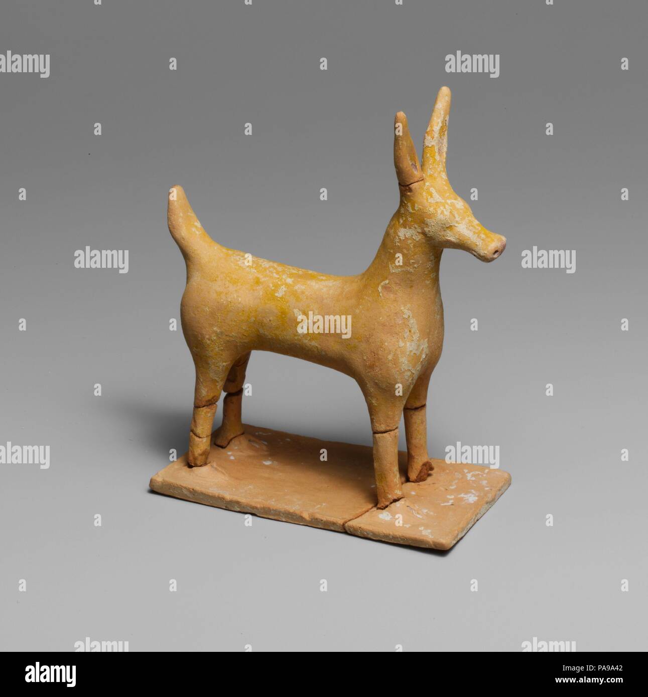 Terracotta statuette of a deer. Culture: Greek. Dimensions: H. 4 7/16 in. (11.3 cm)  Base 1 7/8 x 3 7/8 in. (4.8 x 8.8 cm). Date: late 6th century B.C..  Traces of paint can be seen on this statuette: yellow on the plinth and on the deer; red on all four feet, on the  nose, and inside the ears. Museum: Metropolitan Museum of Art, New York, USA. Stock Photo