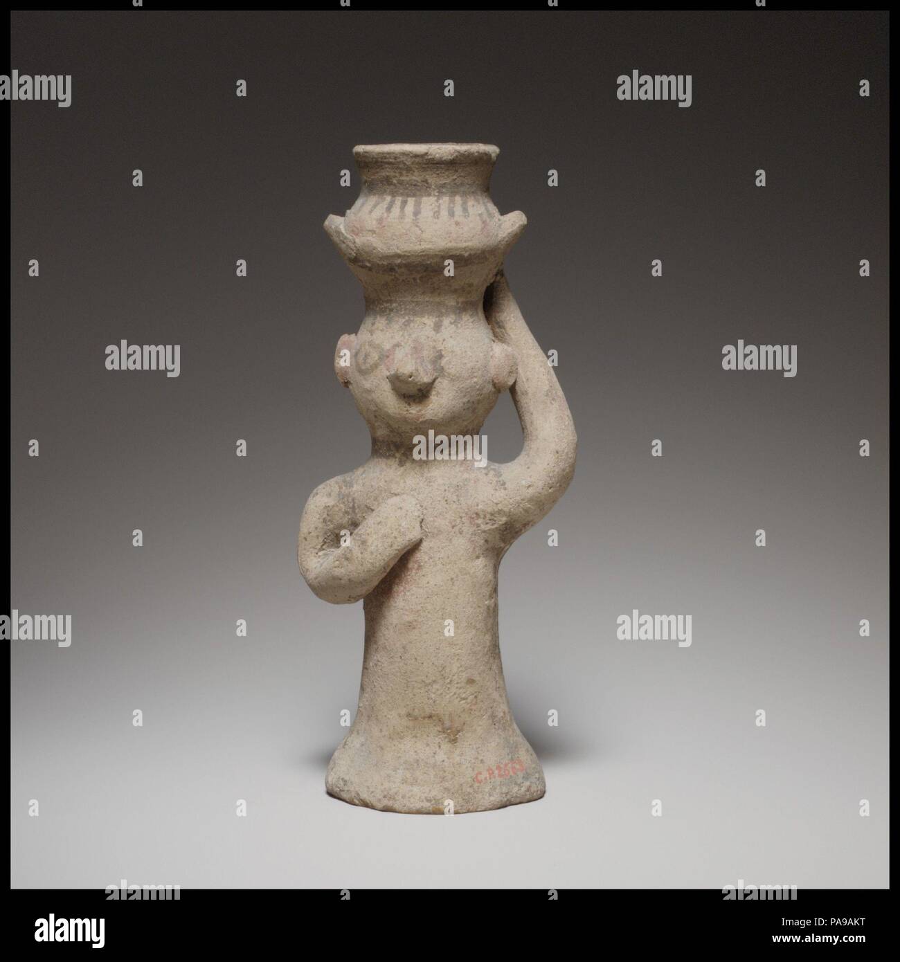 Standing female figurine holding an amphora on her head. Culture: Cypriot. Dimensions: H. 5 5/16 in. (13.5 cm). Date: ca. 750-600 B.C..  The cylindrical body is wheel-made and hollow. The upper part of the body, arms, head, and amphora are handmade. Museum: Metropolitan Museum of Art, New York, USA. Stock Photo