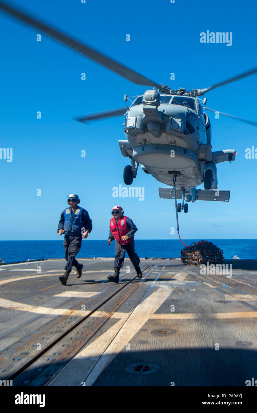 180720-N-HE318-1270 PHILIPPINE SEA (July 20, 2018) Sailors assigned to the Ticonderoga-class guided-missile cruiser USS Antietam (CG 54) egress after securing a cargo hook to a MH-60R Sea Hawk helicopter, assigned to the “Warlords” of Helicopter Maritime Strike Squadron (HSM) 51, as it hovers above the ship’s flight deck. Antietam is forward-deployed in the U.S. 7th Fleet area of operations in support of security and stability in the Indo-Pacific region. (U.S. Navy photo by Mass Communication Specialist 2nd Class William McCann/Released) Stock Photo