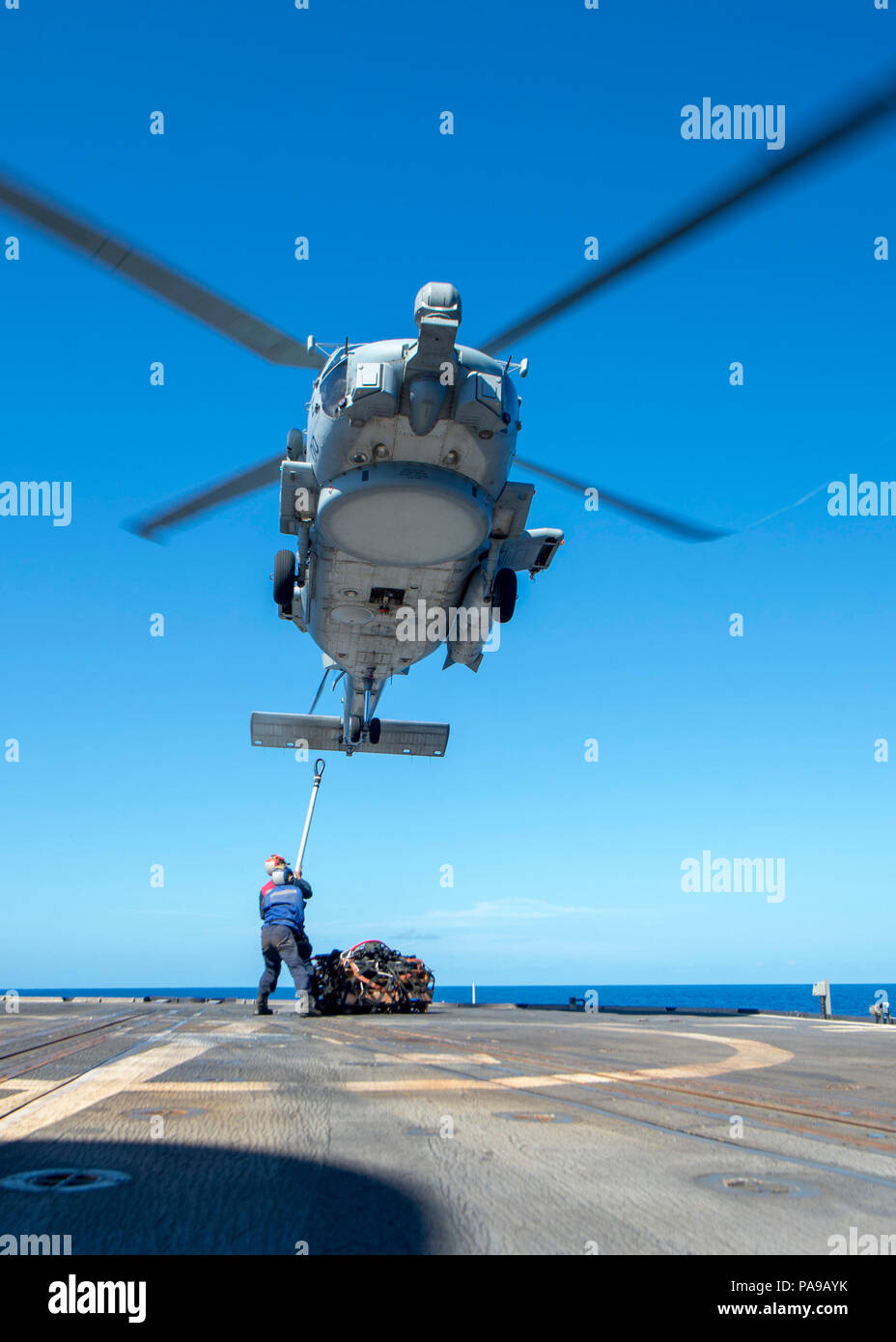 180720-N-HE318-1120 PHILIPPINE SEA (July 20, 2018) Sailors assigned to the Ticonderoga-class guided-missile cruiser USS Antietam (CG 54) prepare to attach a cargo hook to a MH-60R Sea Hawk helicopter, assigned to the “Warlords” of Helicopter Maritime Strike Squadron (HSM) 51, as it hovers above the ship’s flight deck. Antietam is forward-deployed in the U.S. 7th Fleet area of operations in support of security and stability in the Indo-Pacific region. (U.S. Navy photo by Mass Communication Specialist 2nd Class William McCann/Released) Stock Photo