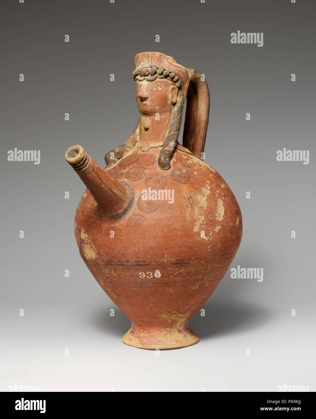 Terracotta trick vase. Culture: Cypriot. Dimensions: H. 10 1/2 in. (26.7 cm). Date: 750-600 B.C..  The spout and neck are in the form of a woman's head. The 'trick' in the vase consists of a hole in the underside of the foot. When the opening was unplugged, the contents of the vase would flow out. Museum: Metropolitan Museum of Art, New York, USA. Stock Photo