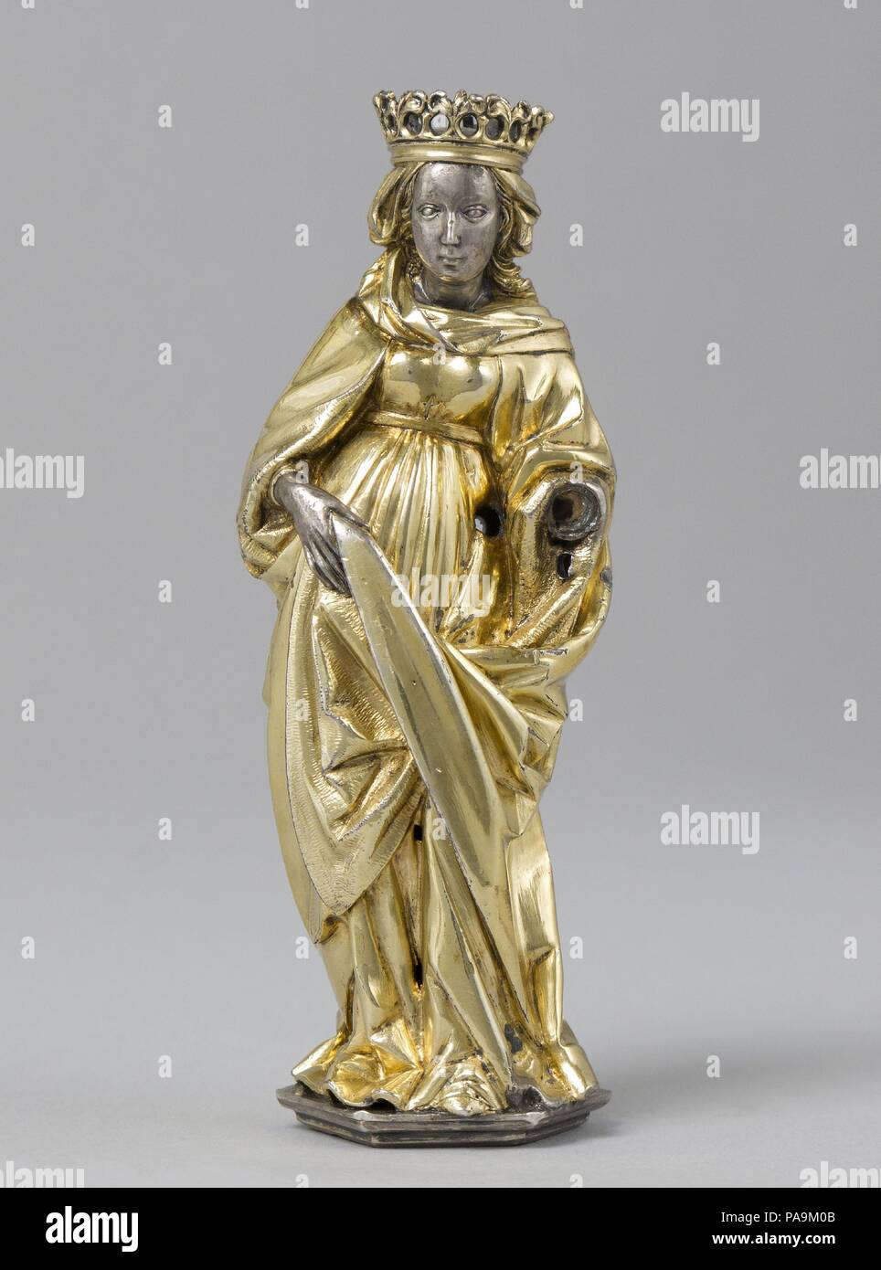 Standing Female Saint. Artist: Hans von Reutlingen (German, Aachen, 1465-1547) or Workshop. Culture: German. Dimensions: Overall: 3 3/4 x 1 5/16 x 1 1/4in. (9.5 x 3.4 x 3.1cm). Date: ca. 1510.  This finely worked figure appears to have come from the immense bust reliquary of Saint Lambert commissioned by the prince-bishop Erard de La Marck for the now-destroyed cathedral of Saint Lambert in Liège. Created by the Aachen goldsmith Hans von Reutlingen and his workshop beginning in 1508, it was consecrated on April 22, 1512. The left hand of the crowned female figure is also missing, together with Stock Photo