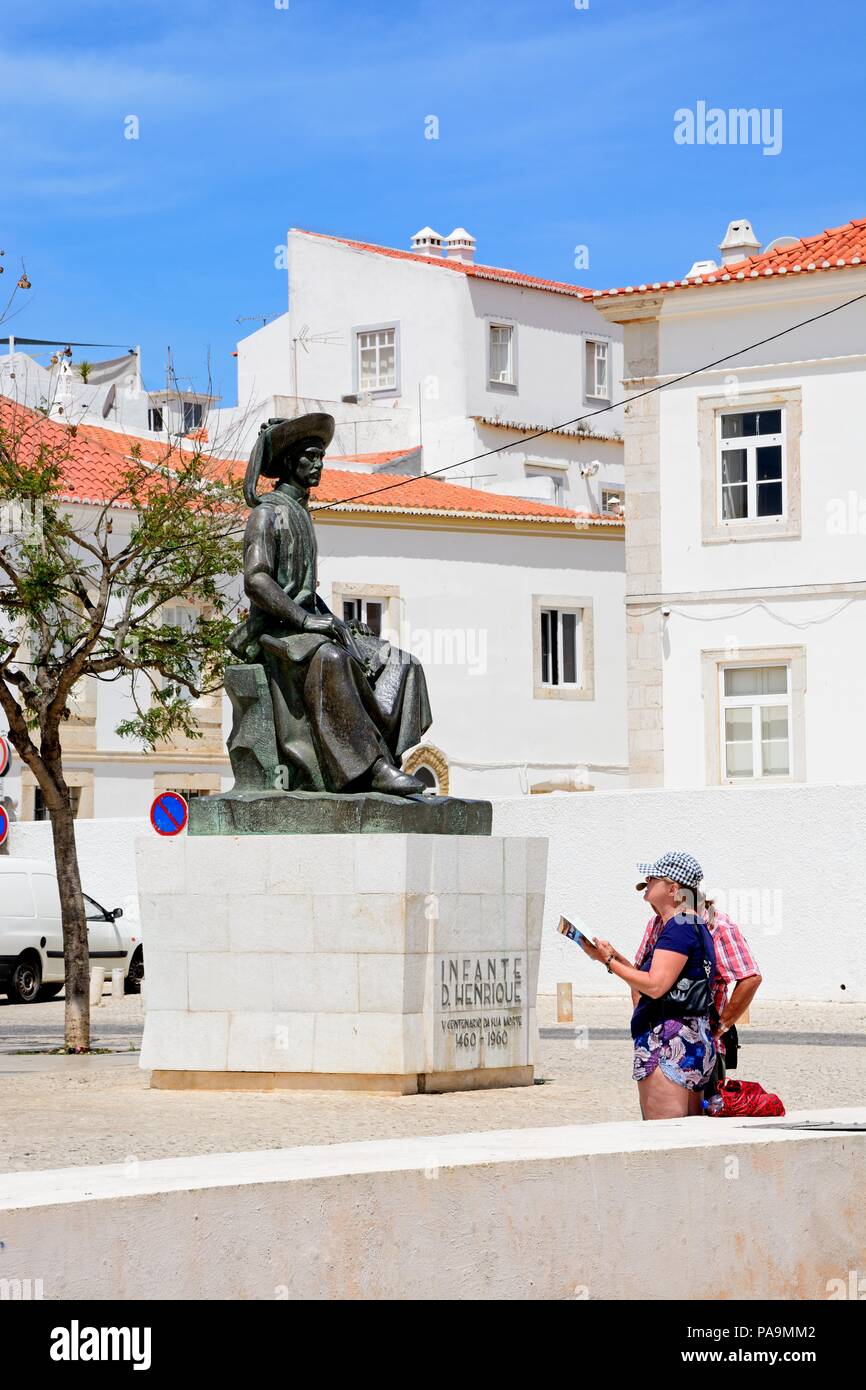 A couple looking at a map facing the statue of Infante Dom Henrique (Prince Henry) in the town square with town buildings to the rear, Lagos, Algarve, Stock Photo