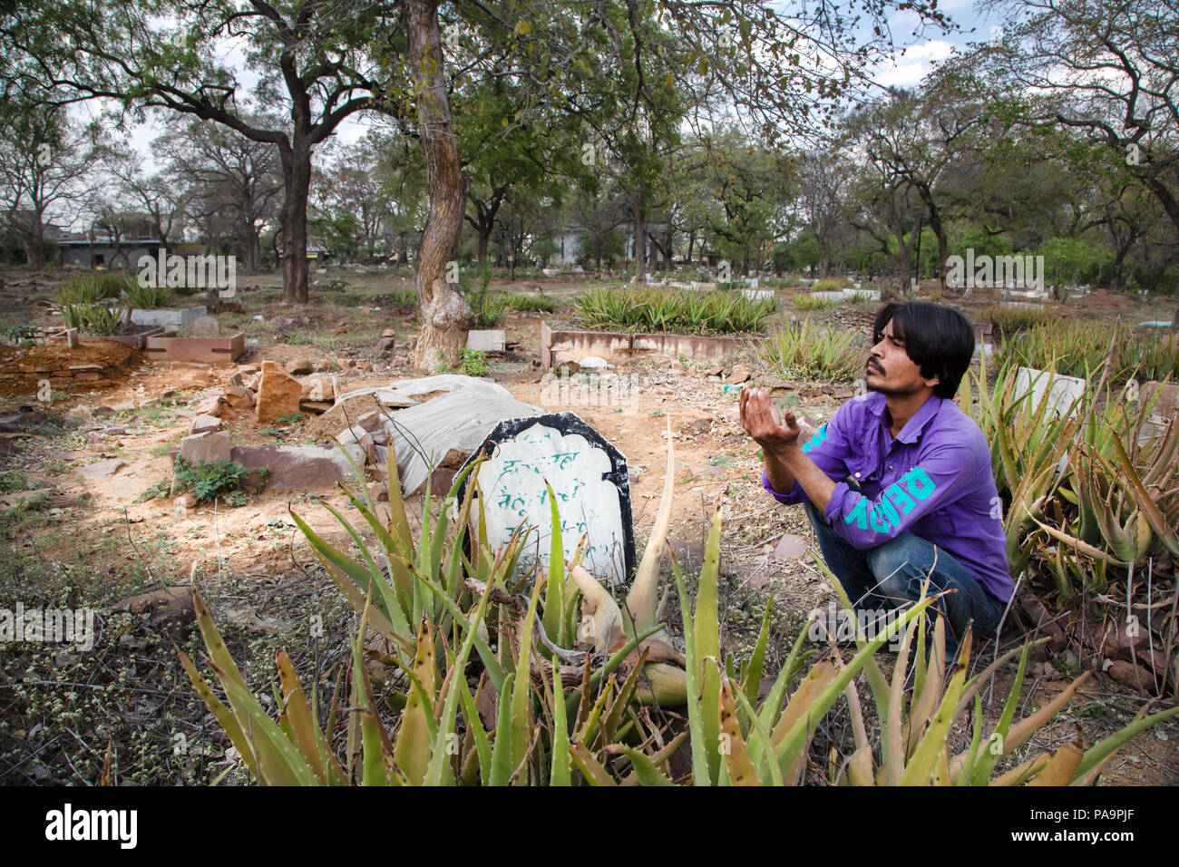 Man praying in cemetery where the victims of the 1984 disaster were buried Bhopal, India Stock Photo