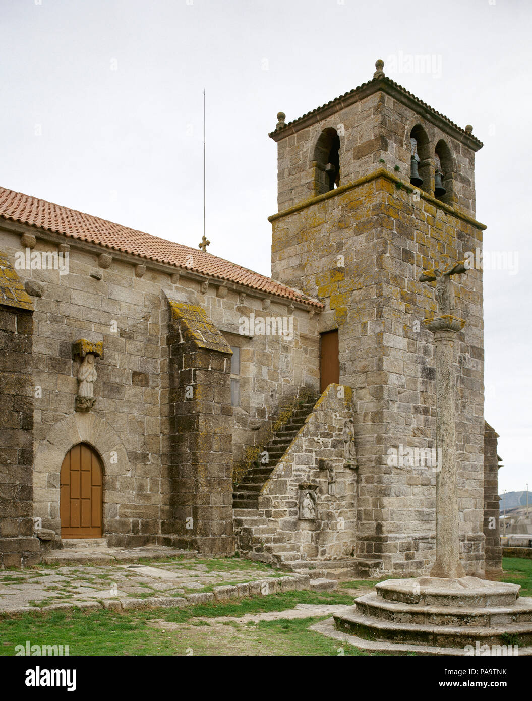 Ponteceso, La Coruña province, Galicia, Spain. The church of Santa Maria da Atalaia. It was built at the end of 14th century in Gothic sailor style, by Dame Urraca de Moscoro by express wish of his mother Dame Juana de Castro and Lara. Bell tower and calvary stone. Stock Photo