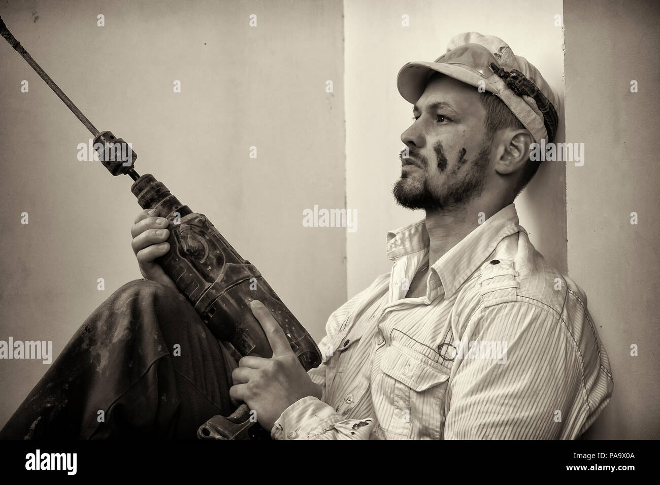 Tiler sitting with a puncher in hands and pondered Stock Photo