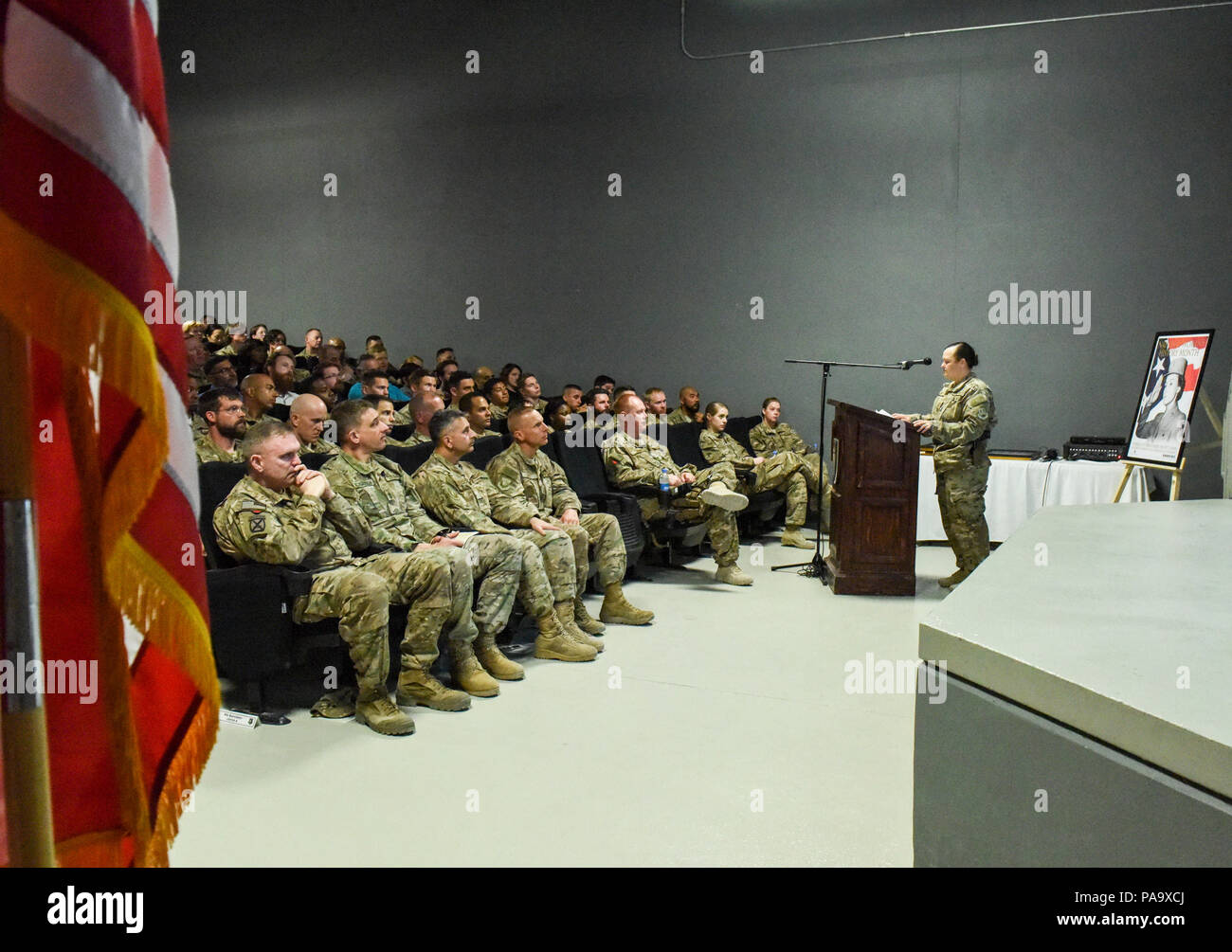Chief Master Sgt. Shelley Haskett, 455th Expeditionary Mission Support Group chief enlisted manager, speaks about the accomplishments of Senior Airman Breanne Balk, 455th Expeditionary Security Forces Squadron Fly Away Security Team member, during a Women’s History Month event at Bagram Air Field, Afghanistan, March 5, 2016. The event told the profiles in courage of five women from around the base who have made impact on their fellow service members and civilians. Balk was highlighted for her efforts to control the bleeding of an injured service member during an airlift to the Craig Joint-Thea Stock Photo
