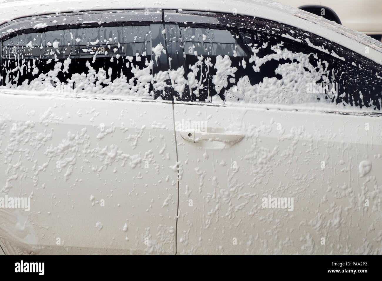 Cleaning car with foam at car wash shop. Stock Photo