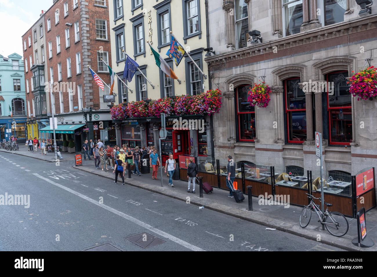 Students, tourists and pedestrians with backpacks walk along a city