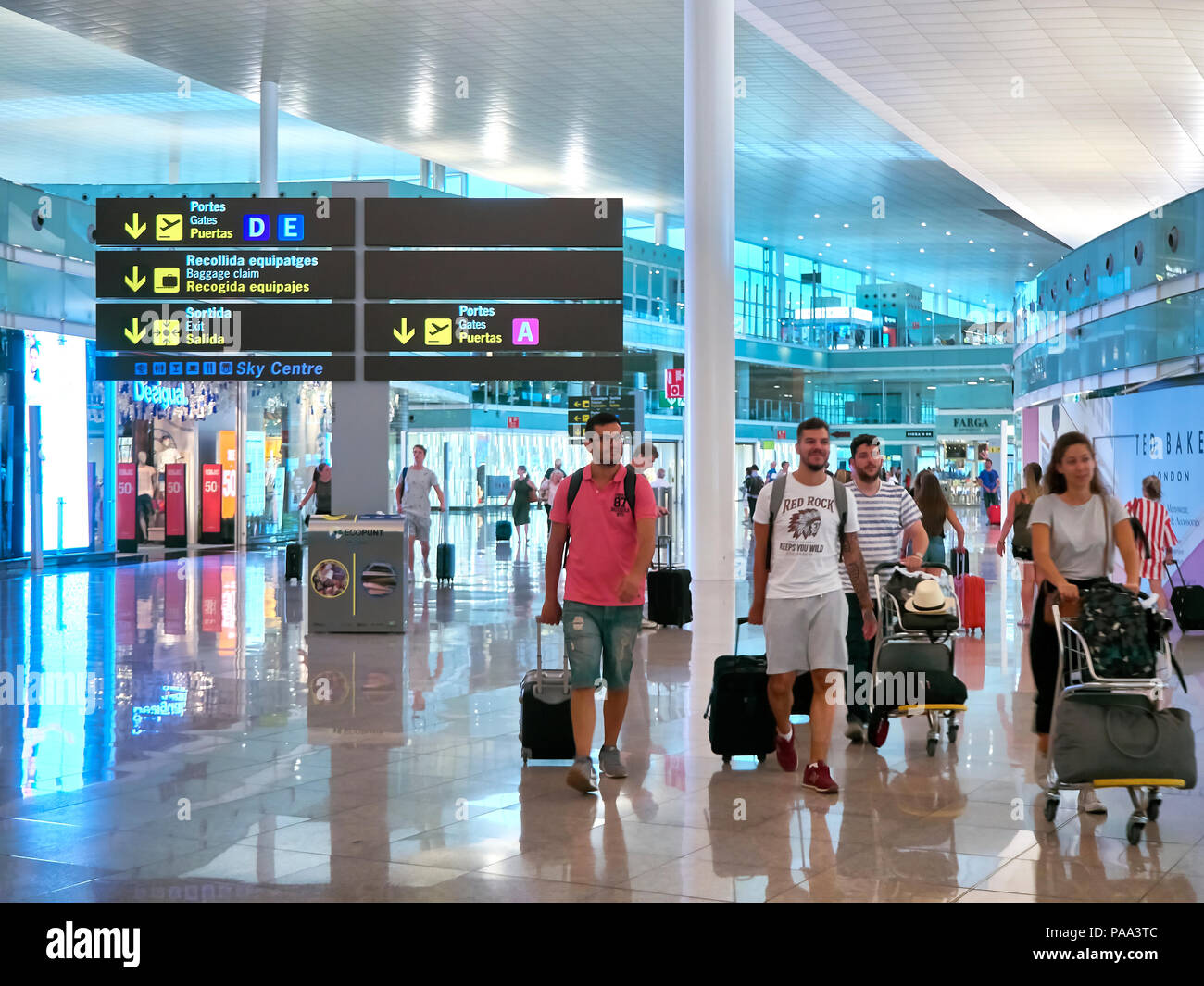 Barcelona, Spain - June 28, 2018. Passengers in transit in a Terminal of Barcelona international airport with a Dutyfree stores in background. Barcelo Stock Photo