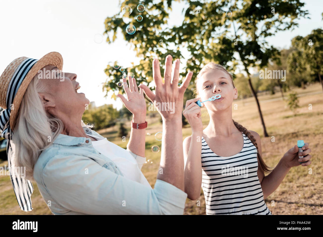 Joyful elderly woman catching bubbles Stock Photo