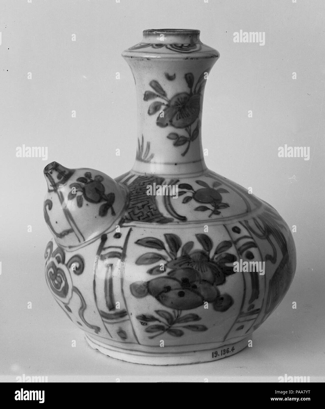 Pouring Vessel (Kendi) with Flowers and Fruits. Culture: China. Dimensions: H. 7 3/8 in. (18.7 cm); W. 5 1/2 in. (14 cm). Date: late 16th century.  Chinese manufacture of this drinking vessel with a long neck and a spout, known as kendi (a Malay word), began during the fourteenth century for export to Muslim communities in Southeast Asia. By the sixteenth century it was carried farther afield to the Middle East, where Persian copies were made. This late sixteenth-century version, not necessarily made for export to Europe, is decorated in patterns that commonly were applied to kraak porcelain.  Stock Photo