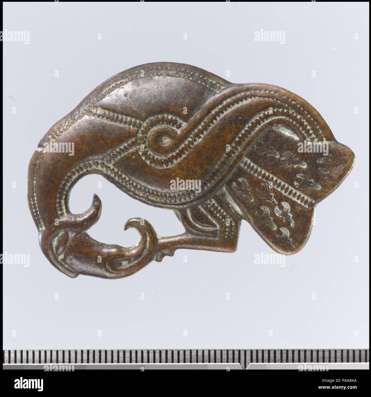 Brooch in Form of a Bird of Prey. Culture: Vendel. Dimensions: Overall: 2 1/8 x 1 1/4 x 3/8 in. (5.4 x 3.2 x 1 cm). Date: late 500s.  The head and right leg of this elegant bird brooch are in left profile, while its rounded body and flaring tail are presented frontally. The extended right wing curves behind the tail. The edges of the neck, wings, and tail, and the upper part of the leg are outlined with pseudobeading. Nine stamped (punched?) crayfish decorate the tail. The position of the head, supported by the raised leg, indicates that the bird is sleeping. Museum: Metropolitan Museum of Art Stock Photo