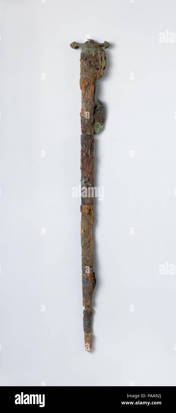 Sword. Dimensions: 1 3/8 x 28 1/8 in. (3.5 x 71.5 cm). Date: 9th century.  This sword has an iron blade and was adorned with gilt-bronze elements on the cross guard and quillon. Parts of its wooden scabbard remain fused to the blade, which also was decorated with gilt-bronze mounts at the center and tip. The form of this sword, with its straight, double-edged blade, seems to be a Central Asian type. Museum: Metropolitan Museum of Art, New York, USA. Stock Photo