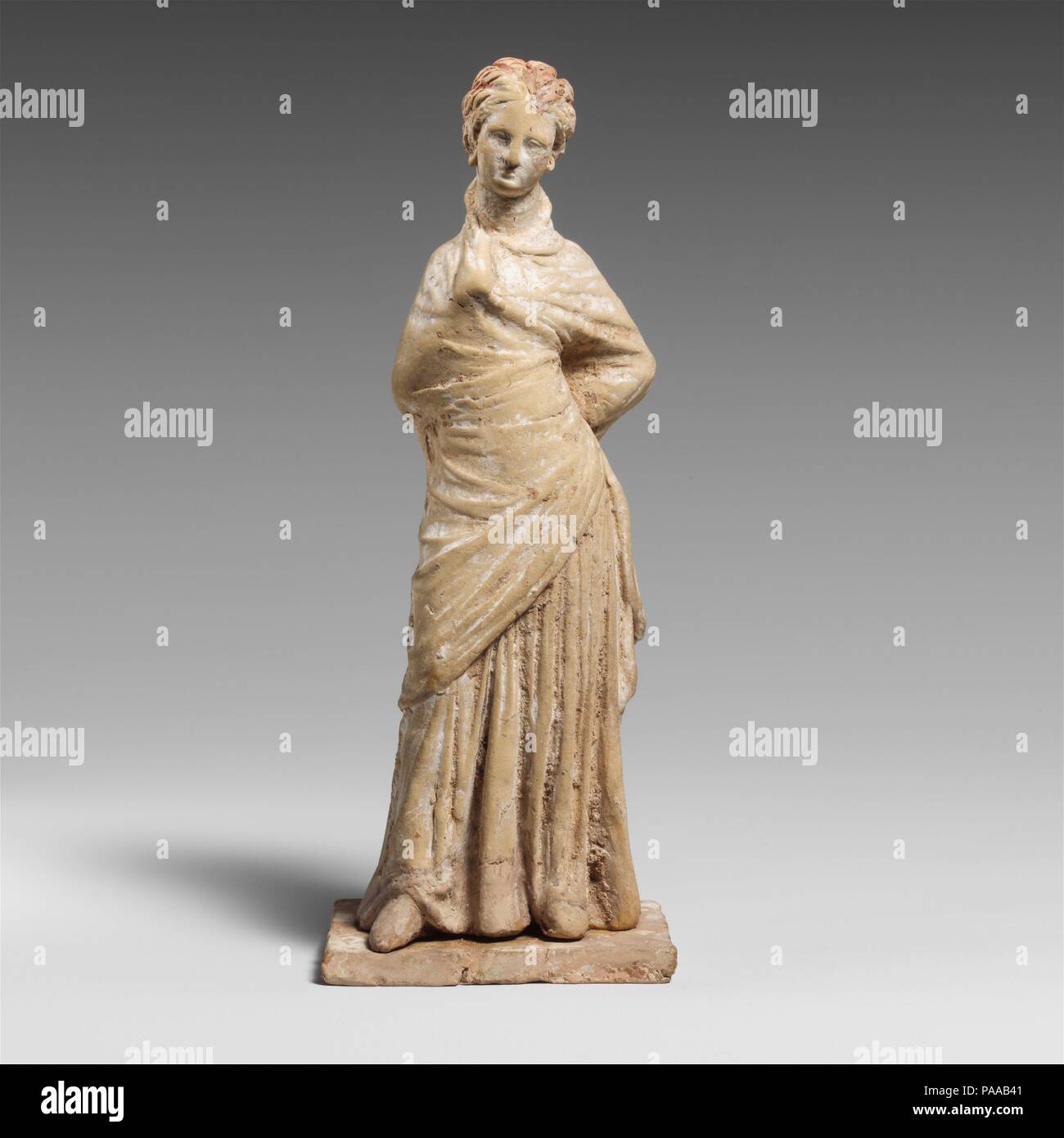 Terracotta statuette of a draped woman. Culture: Greek, Boeotian. Dimensions: H.: 6 7/16 in. (16.4 cm). Date: mid-3rd century B.C..  The play of this lady's drapery is enlivened by her right arm bent under her garment and her left arm held akimbo. Considerable color is preserved on her hair. Museum: Metropolitan Museum of Art, New York, USA. Stock Photo