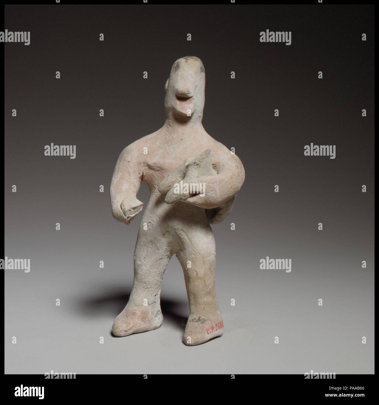 Standing male figurine holding a quadruped. Culture: Cypriot. Dimensions: H. 4 7/16 in. (11.3 cm). Date: ca. 600-480 B.C..  The handmade and solid figurine stands with its legs apart. The legs are columnar, the feet rendered with painted shoes. Museum: Metropolitan Museum of Art, New York, USA. Stock Photo