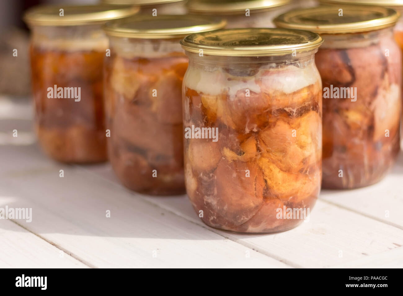 Canned meat in a glass jar on a white wooden table Stock Photo