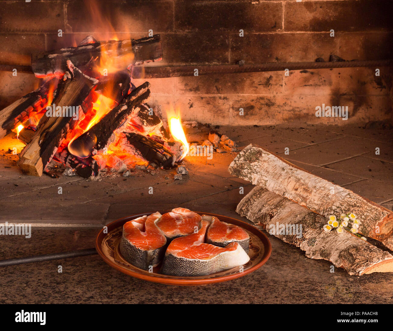 Steaks of fresh salmon near burning firewood Stock Photo