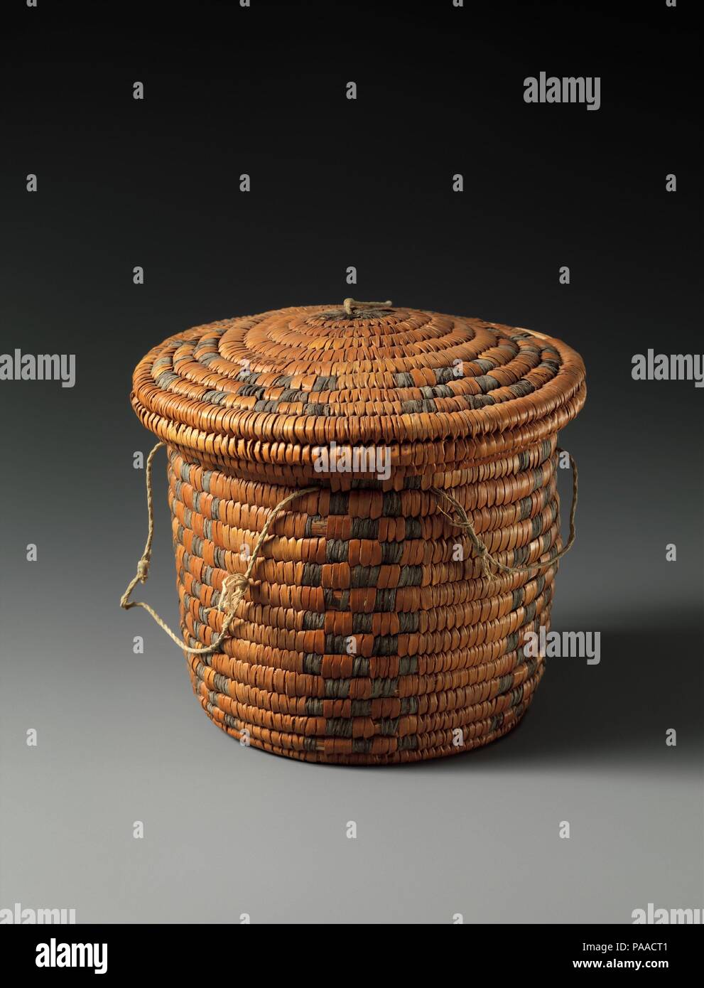 Cylindrical Coil Basket and Lid. Dimensions: Basket: H. 10.6 cm (4 6/16 in.); Diam. 11 cm (4 5/16 in.)  Lid: H. 3.2 cm (1 1/4 in.); Diam. 13 cm (5 1/8 in.). Dynasty: Dynasty 11. Date: ca. 2124-2000 B.C..  This cylindrical basket with a matching lid was found to the right of the door of an Eleventh Dynasty tomb. Nested inside the basket was another smaller basket of similar shape. When the excavators opened the two containers, they were surprised to find a small collection of personal objects, including bits of malachite wrapped in a piece of linen cloth, a lump of wax, raisins, several pieces  Stock Photo