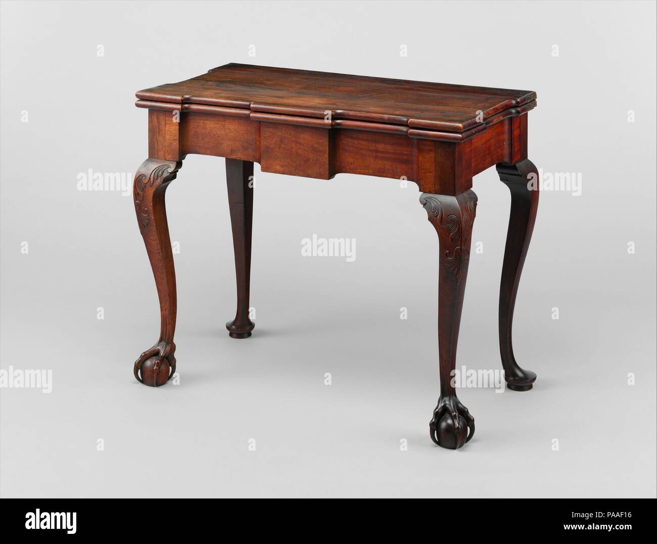 Card Table. Culture: American. Dimensions: 27 3/4 x 33 1/4 x 16 1/2 in. (70.5 x 84.5 x 41.9 cm). Maker: Attributed to John Goddard (1724-1785). Date: 1760-90.  On this exquisite exemplar of a Newport cabriole-leg card table, the various elements of the skirt board are in perfect proportion and equilibrium, the curves of the legs are altogether satisfying, and the carved bird's talons grasping the ball feet appear alive. This is poetry in wood, something only John Goddard, of all the Newport makers, could on occasion achieve. Museum: Metropolitan Museum of Art, New York, USA. Stock Photo