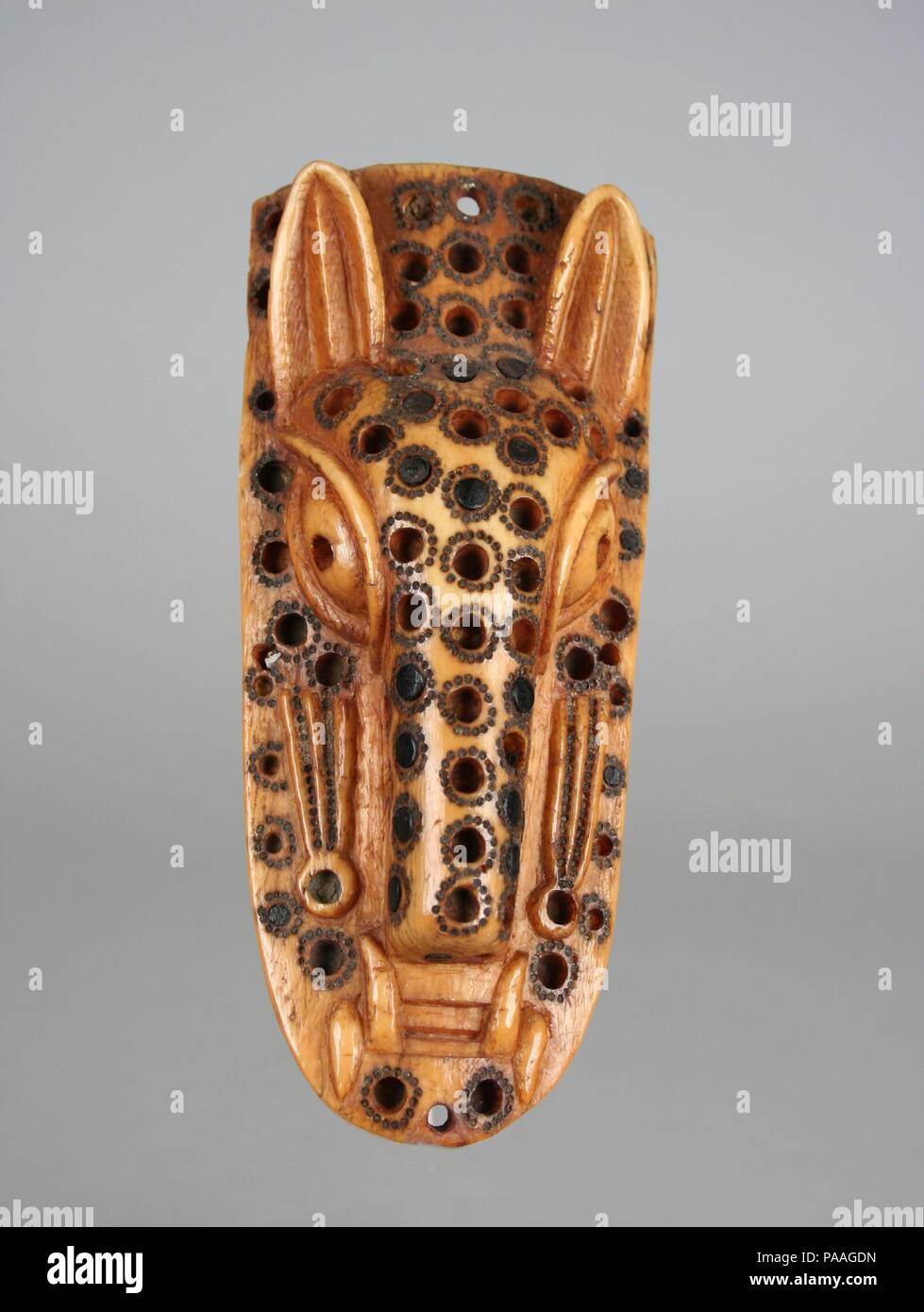 Masquerade Element: Leopard Head (Omama). Culture: Yoruba peoples, Owo group. Dimensions: H. 6 x W. 2 1/2 x D. 1 1/8 in. (15.2 x 6.4 x 2.8 cm). Date: 17th-19th century.  The influence of Benin royal art is particularly apparent in Owo, a Yoruba kingdom that came under Benin control in the fifteenth century and again in the eighteenth. Located on the eastern edge of Yorubaland, Owo is almost equidistant from Benin and Ife, the Yoruba cultural and religious center from which the reigning dynasty in Benin traces its origin. Although some Owo artworks resemble the highly naturalistic brass and ter Stock Photo