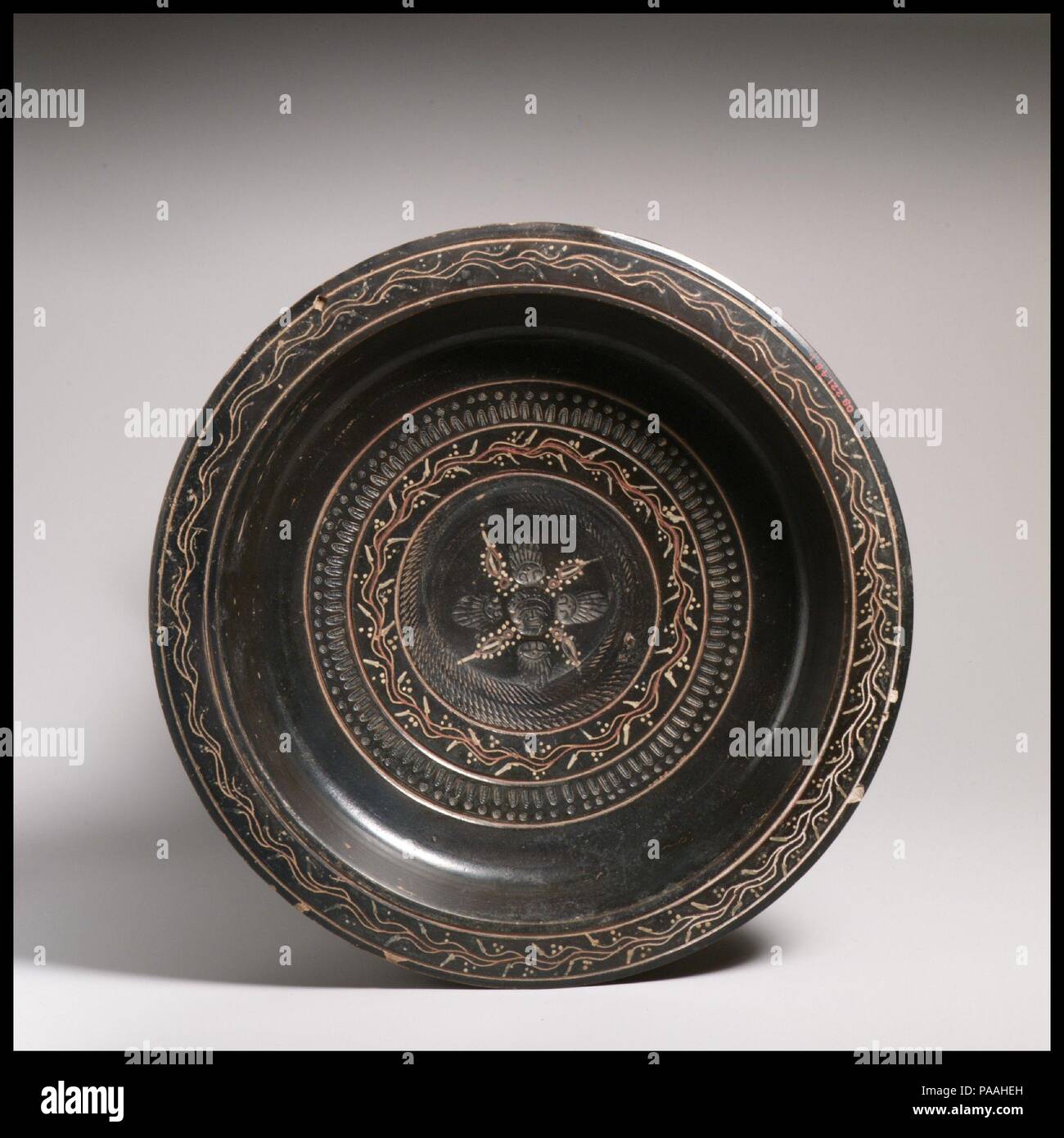 Terracotta dish. Culture: Greek, South Italian, Campanian, Teano. Dimensions: Other: 2 1/2 in. (6.4 cm). Date: ca. 330-300 B.C..  Flat dish with ring base, decorated with ivy vine and stamped pattern. Museum: Metropolitan Museum of Art, New York, USA. Stock Photo
