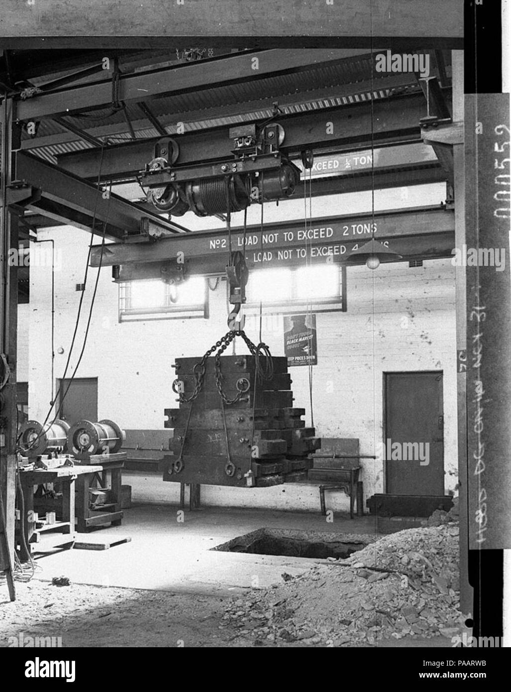 238 SLNSW 13043 Workshop scene showing two ton electric hoist doing a lift Wartime sign Dont help the black market Stock Photo