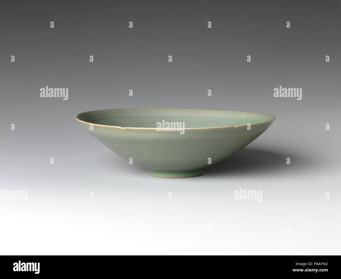 Six-Lobed Bowl. Culture: Korea. Dimensions: H. 2 1/8 in. (5.4 cm); Diam. 7 3/8 in. (18.8 cm); Diam. of foot 2 in. (5.1 cm). Date: early 12th century.  This six-lobed bowl, shaped to look like a flower, exemplifies the elegant purity of early twelfth-century Goryeo celadon. Its clean, minimalist form is unmarked by surface decoration, save for an incised ring around the interior rim of the bowl. The thinly potted body, gray-green glaze, and three small spur marks on the base (evidence that the vessels were stacked during firing) are all characteristic of celadon from this period. Museum: Metrop Stock Photo