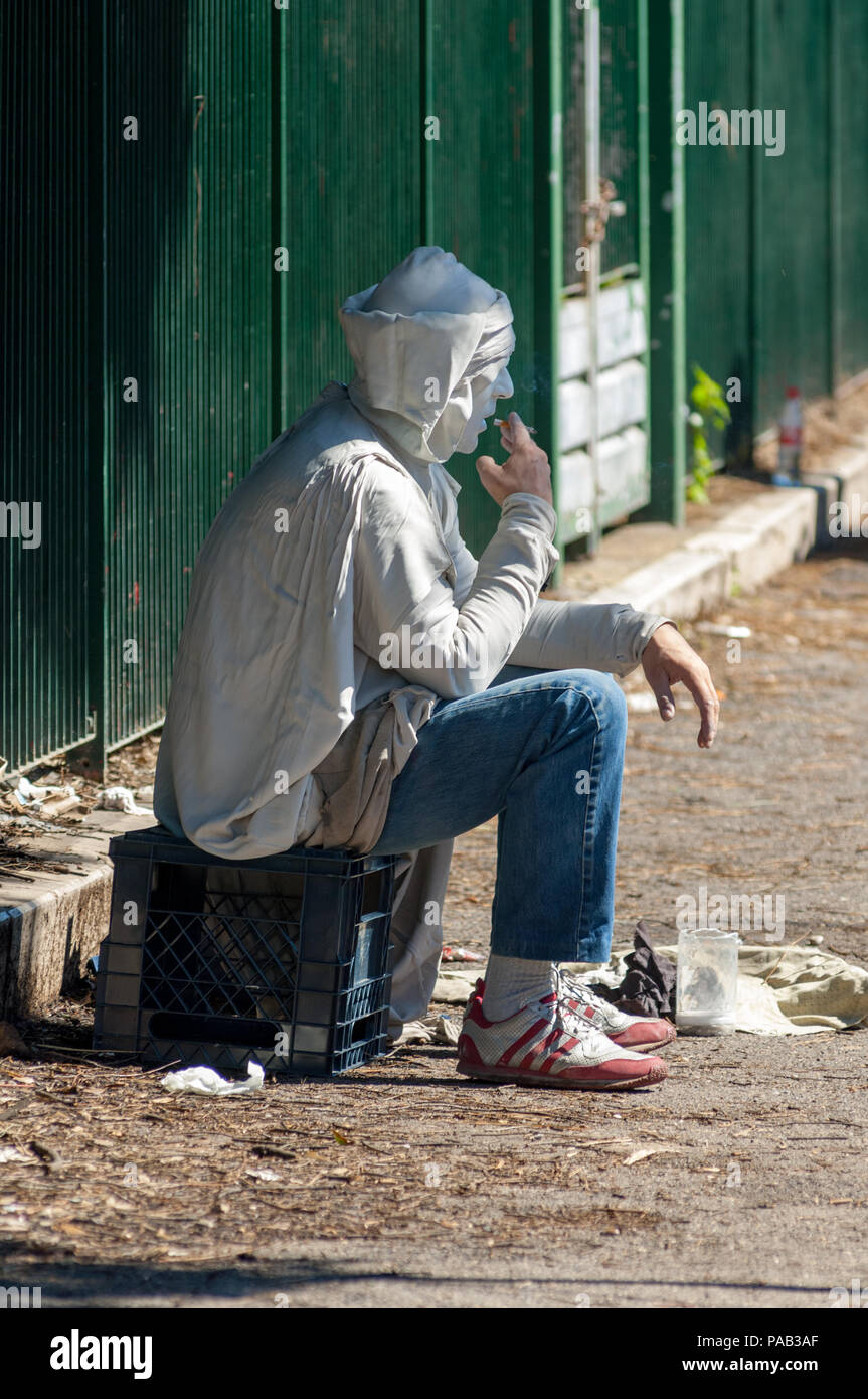 A street artist  takes a quick cigarette break from his living statue performance at the Forum in Rome Stock Photo