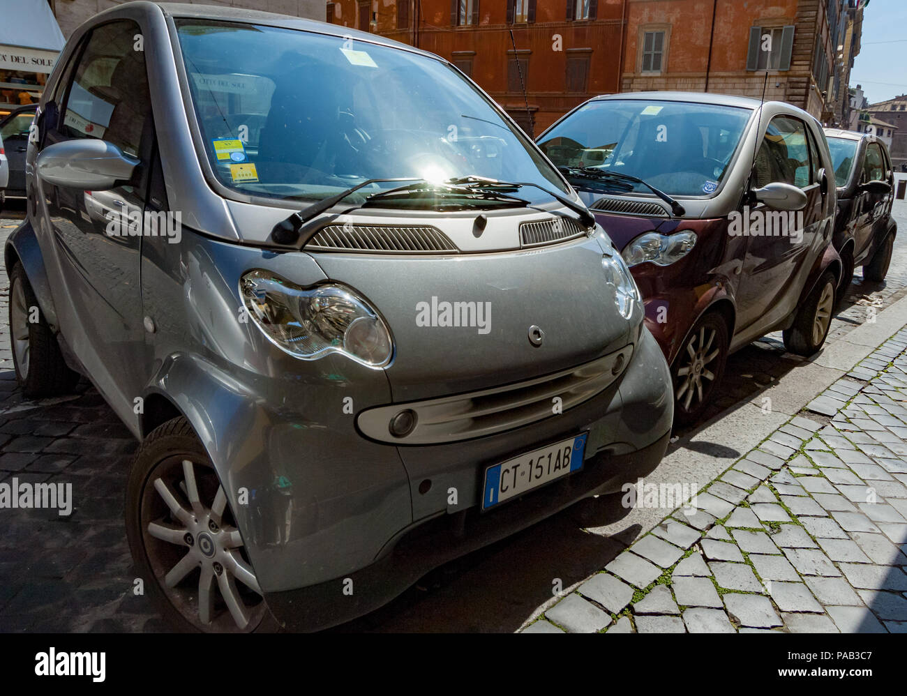 Smart cars parked haphazardly in a Rome street. Stock Photo