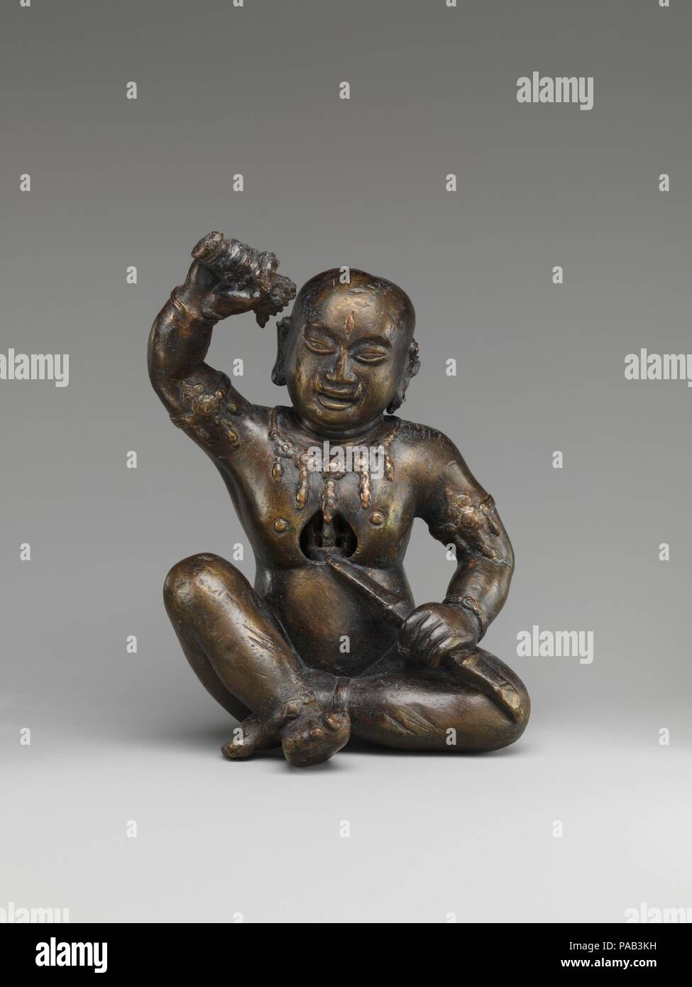 Esoteric Buddhist Personage. Culture: Nepal (Kathmandu Valley). Dimensions: H. 6 3/8 in. (16.2 cm); W. 4 3/8 in. (11.1 cm). Date: 15th century.  This wrathful Tantric Buddhist personage, with a shaved head, a vertical third eye, and upward-pointing fangs, is unidentified. His jewelry derives from eastern Indian prototypes of the Pala period (9th-12th century). He points a single-pronged thunderbolt scepter (vajra) toward a heart-shaped cavity at the center of his chest, itself occupied by a multipronged vajra. In his raised hand he holds a sword pommel with a guard in the shape of a lion's hea Stock Photo
