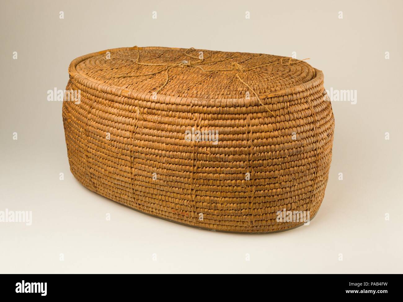 Large Oval Storage Basket. Dimensions: Basket: L. 55 cm (21 5/8 in.); W. 40 cm (15 3/4 in.)  Lid: L. 46.5 cm (18 5/16 in.); w. 33 cm (13 in.)  Overall: H. 24.5 cm (9 5/8 in.). Dynasty: Dynasty 18, early. Reign: reign of Thutmose II-Early Joint reign. Date: ca. 1492-1473 B.C..  This storage basket was discovered in the tomb of Senenmut's mother, Hatnofer (36.3.1), who lived into the reign of Hatshepsut.  The basket is made of halfa grass coils sewn together with strips of palm leaf.  It was tied shut using pieces of linen cords attached around the top edge of the basket. Then a mud seal was pre Stock Photo
