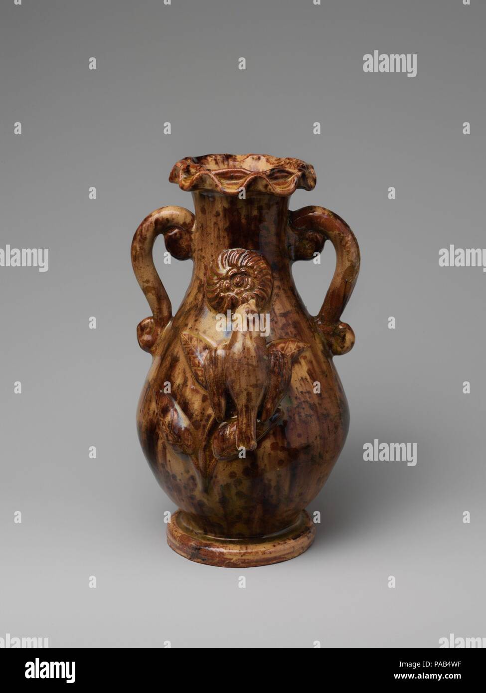 Vase. Culture: American. Dimensions: H. 9 1/2 in. (24.1 cm). Maker: Anthony W. Baecher (1824-1889). Date: 1880-89.  A German immigrant considered one of the most accomplished of the Shenandoah Valley potters, Baecher produced this vase in a primitive Rococo-style scheme. Although he repeatedly employed lowrelief pinwheel flowers and sculptural feeding birds as decoration on his hollow ware, archaeological findings reveal that simple storage jars were the mainstay of his production. Museum: Metropolitan Museum of Art, New York, USA. Stock Photo