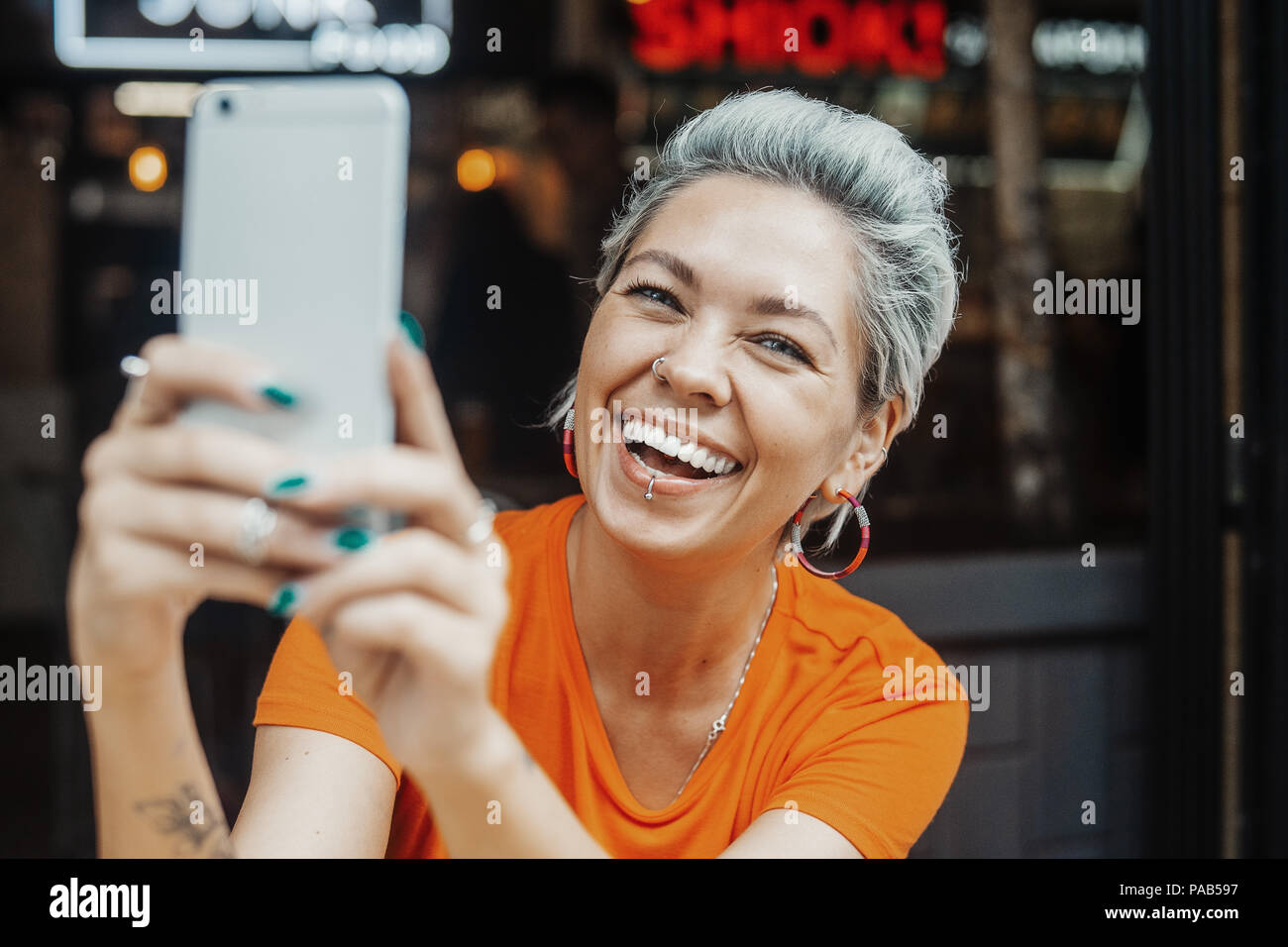 Attractive Positive Blonde Woman In Orange T Shirt Making Selfie At