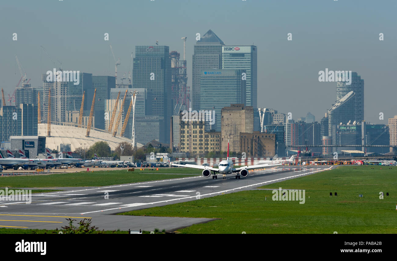Airbus A220-100 landing at London City Airport, with the towers of Canary Wharf and The O2 in the background Stock Photo