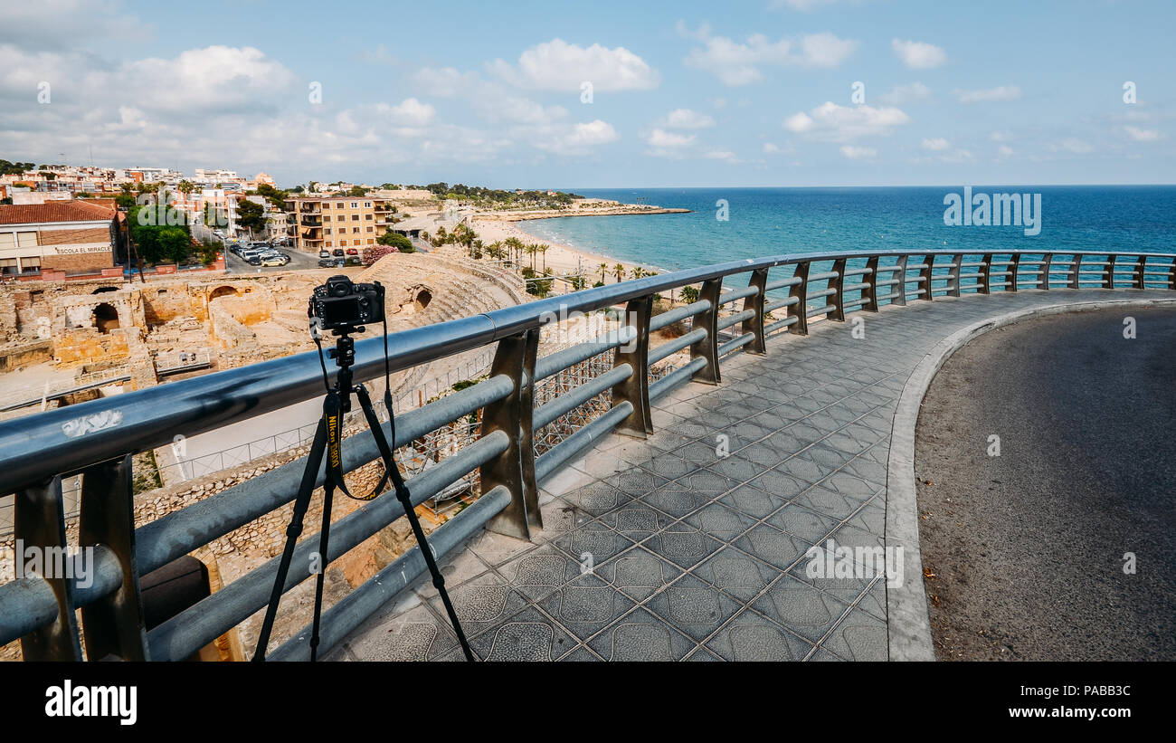 Tarragona, Spain - July 11, 2018: Illustrative editorial of Nikon D800 DSLR and tripod with panoramic view of the ancient roman amphitheater of Tarrag Stock Photo
