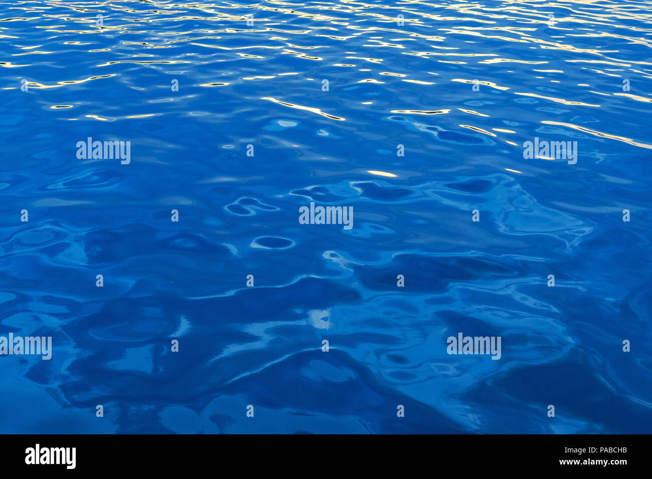 Calm water at sea with some small ripples and waves in clear blue ...