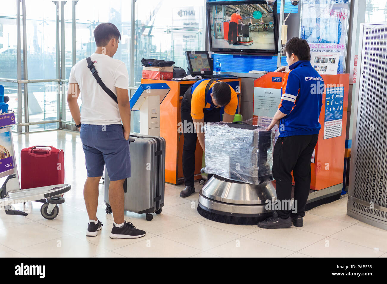 BANGKOK, THAILAND 21 JULY 2018 Men at airport luggage wrapping