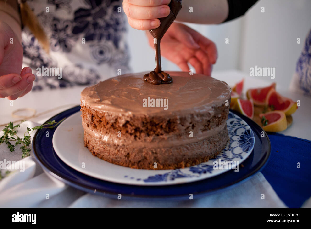 Home confectionery. Two girls making a cake on the kitchen.Women cooking a cake with chocolate cream. Family cooking Stock Photo