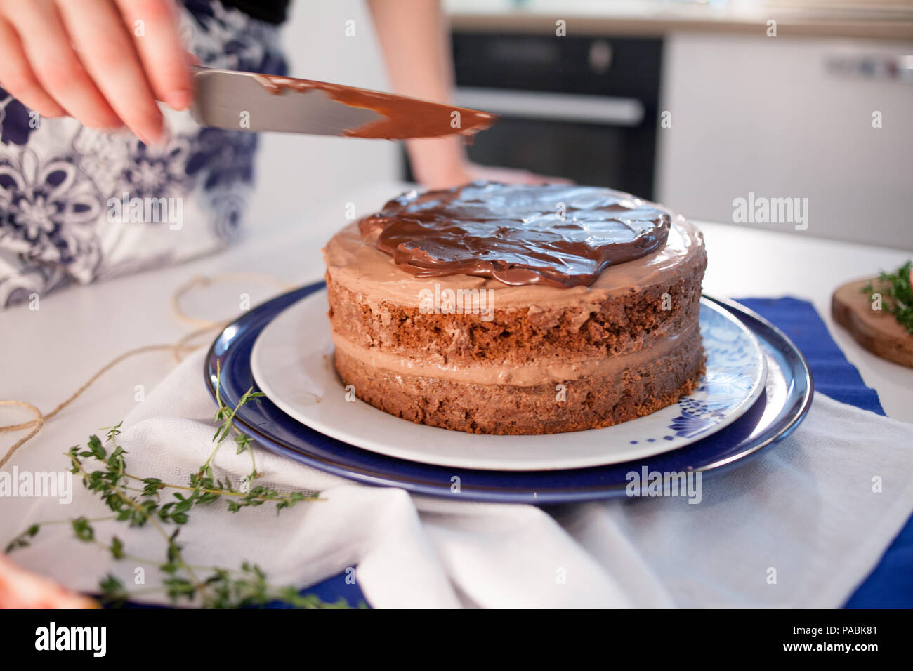 Home confectionery. Two girls making a cake on the kitchen.Women cooking a cake with chocolate cream. Family cooking Stock Photo