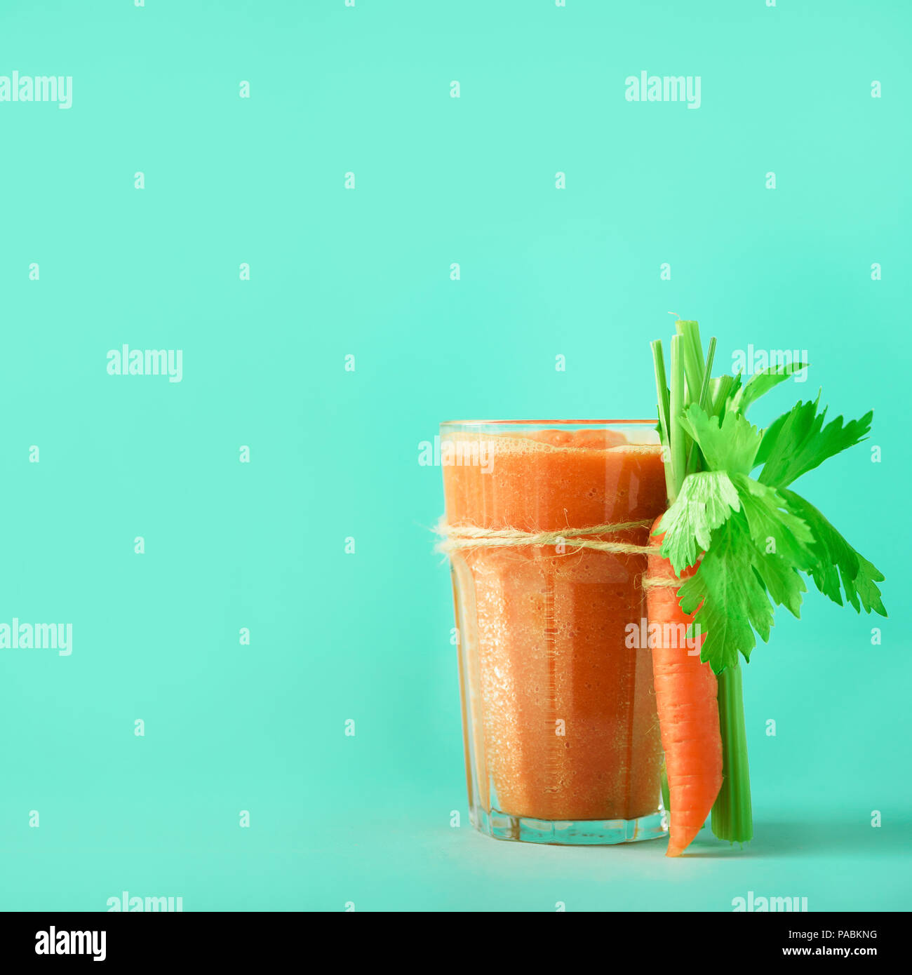 Fresh organic carrot juice with carrots, celery on blue background. Square crop. Vegetable smothie in glass. Banner. Copy space. Summer food concept.  Stock Photo