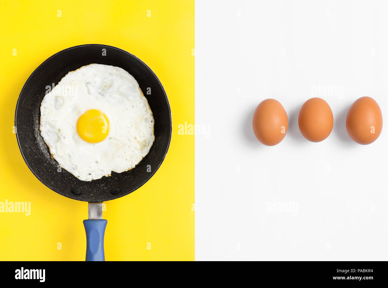 Split color flat lay image with cooked egg in a a pan and uncooked eggs